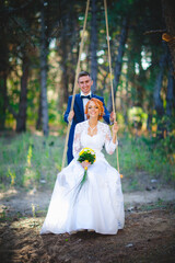 Young beautiful couple in a blue suit and white wedding dress with a bouquet