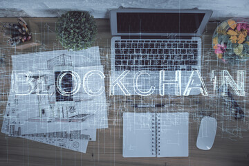 Blockchain theme hologram drawings over computer on the desktop background. Top view. Double...