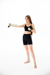 Fototapeta premium A beautiful girl in sportswear is training with an expander on a white background. Hand exercise
