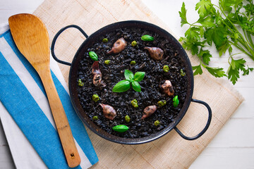 Black paella with squid and pistachio pesto. Tapa paella typical recipe from the Spanish Mediterranean coast.