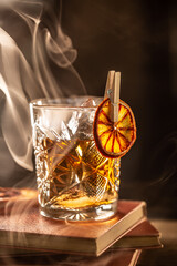 Fototapeta Smoked old fashioned rum cocktail with cubes of ice around on a dark background. obraz