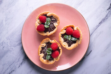 Puff pastry tartlets with chocolate and raspberries. French dessert recipe.