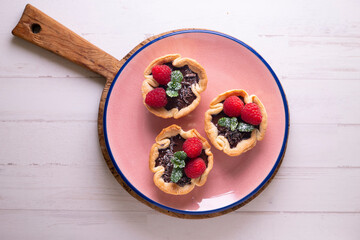 Puff pastry tartlets with chocolate and raspberries. French dessert recipe.