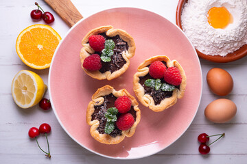 Puff pastry tartlets with chocolate and raspberries. French dessert recipe.