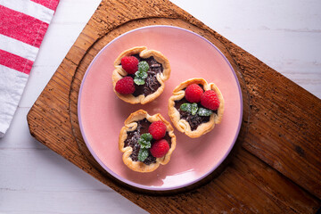 Puff pastry tartlets with chocolate and raspberries. French dessert recipe.