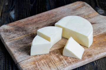 Fresh cow's milk cheese is cut on a board