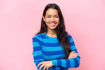 Fototapeta premium Young Colombian woman isolated on pink background with arms crossed and looking forward