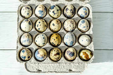 Quail eggs in eco-friendly packaging made from recycled paper, on white wooden table background