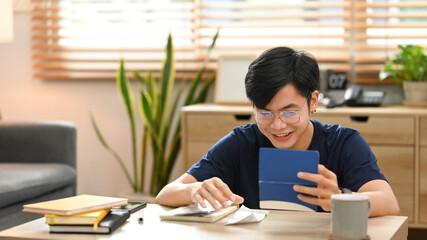 Happy asian man calculating money bank loan and managing expenses finances in living room. Household finance concept