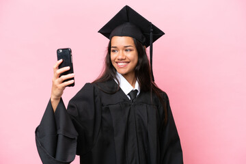 Young university Colombian woman graduate isolated on pink background making a selfie