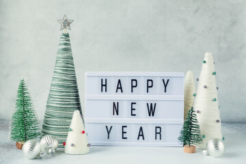 Lightbox with text HAPPY NEW YEAR with yarn wrapped XMAS cone trees. New year celebration. Happy...