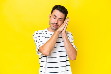 Young handsome man over isolated yellow background making sleep gesture in dorable expression