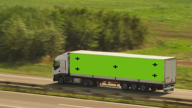 Aerial shot of a fast truck on the road with chroma key greenscreen on the body in beautiful countryside