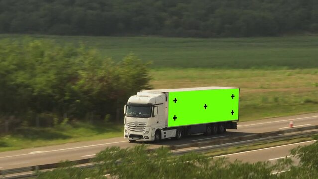 Aerial video of truck with green screen and trackink markers driving on the busy highway road in countryside