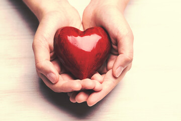 Red wood heart in child hands.