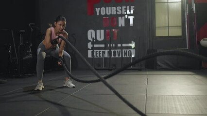 Active dedicated motivated asian female athlete training in gym with battle ropes,determined confident girl enjoying bodybuilding achieving goals with healthy lifestyle.