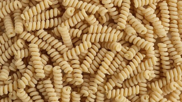 Gluten Free Cornmeal Pasta Wallpaper. Spiral Raw Macaroni from Corn and Rice flour rotating on Turntable. Close Up Top View. Uncooked Pasta Spinning. Full Frame. Food Background. Fusilli Bucati Corti.