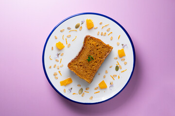 Orange sponge cake seen from above decorated with a few slices of fruit.