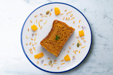 Orange sponge cake seen from above decorated with a few slices of fruit.