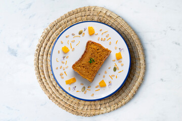 Orange sponge cake seen from above decorated with a few slices of fruit.