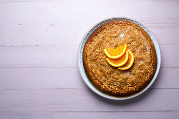 Orange sponge cake seen from above decorated with a few slices of fruit.