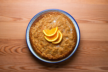 Orange sponge cake seen from above decorated with a few slices of fruit.