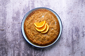 Orange sponge cake seen from above decorated with a few slices of fruit.