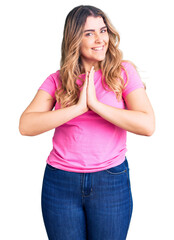 Young caucasian woman wearing sportswear praying with hands together asking for forgiveness smiling confident.