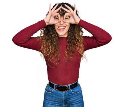 Young hispanic girl wearing casual clothes doing ok gesture like binoculars sticking tongue out, eyes looking through fingers. crazy expression.