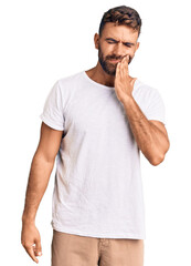 Young hispanic man wearing casual white tshirt touching mouth with hand with painful expression because of toothache or dental illness on teeth. dentist