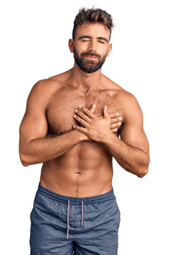 Young hispanic man wearing swimwear shirtless smiling with hands on chest with closed eyes and grateful gesture on face. health concept.