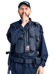 Young handsome man wearing police uniform asking to be quiet with finger on lips. silence and secret concept.