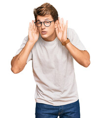 Handsome caucasian man wearing casual clothes and glasses trying to hear both hands on ear gesture, curious for gossip. hearing problem, deaf