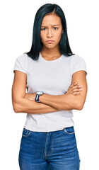 Beautiful hispanic woman wearing casual white tshirt skeptic and nervous, disapproving expression on face with crossed arms. negative person.