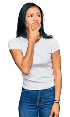 Beautiful hispanic woman wearing casual white tshirt thinking worried about a question, concerned and nervous with hand on chin