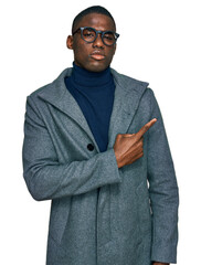 Young african american man wearing business clothes and glasses pointing with hand finger to the side showing advertisement, serious and calm face