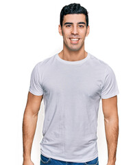 Handsome hispanic man wearing casual white t shirt with a happy and cool smile on face. lucky person.