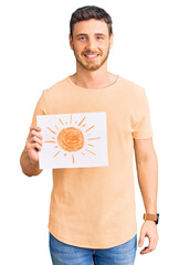 Handsome young man with bear holding sun draw looking positive and happy standing and smiling with...