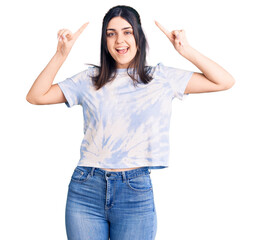 Young beautiful girl wearing casual t shirt smiling amazed and surprised and pointing up with fingers and raised arms.