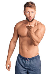 Fototapeta premium Young caucasian man standing shirtless looking at the camera blowing a kiss with hand on air being lovely and sexy. love expression.