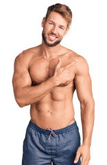 Fototapeta premium Young caucasian man standing shirtless cheerful with a smile of face pointing with hand and finger up to the side with happy and natural expression on face