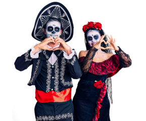 Young couple wearing mexican day of the dead costume over background smiling in love doing heart symbol shape with hands. romantic concept.