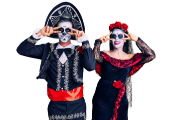 Young couple wearing mexican day of the dead costume over background doing peace symbol with fingers over face, smiling cheerful showing victory