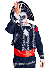 Young man wearing day of the dead costume over background surprised with hand on head for mistake, remember error. forgot, bad memory concept.