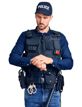 Young handsome man wearing police uniform checking the time on wrist watch, relaxed and confident