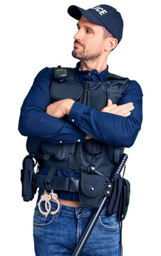 Young handsome man wearing police uniform looking to the side with arms crossed convinced and confident
