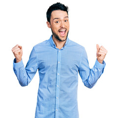 Naklejka premium Hispanic man with beard wearing casual business shirt celebrating surprised and amazed for success with arms raised and open eyes. winner concept.