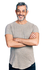Middle age hispanic with grey hair wearing casual grey t shirt happy face smiling with crossed arms...