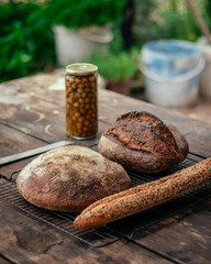 Pan sobre mesa de madera acompañado con Tarro de aceitunas y cuchillo