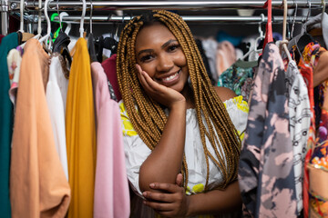 An African woman props her head with her hand and smiles innocently. Clothing store.